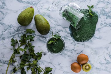 Mermer bir masada cam bardakta spirulinalı yeşil meyve püresi. Süper yiyecek konsepti. Üst Manzara. Yumuşak odak.