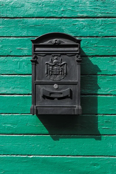 black mailbox on a green wooden boards