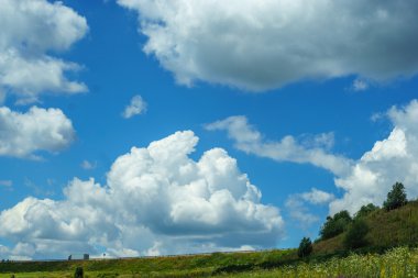 Parlak mavi gökyüzü yüksek bulutlar, doğal sahne, tepenin üstünde belgili tanımlık yol ile