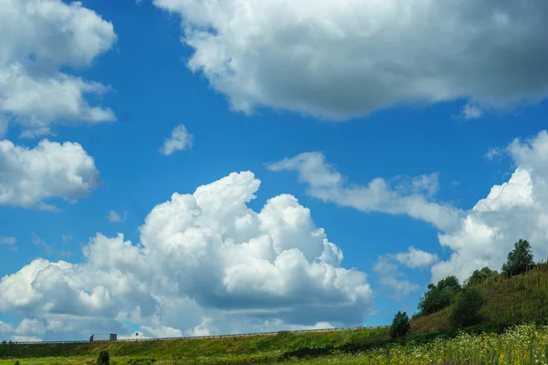 Parlak mavi gökyüzü yüksek bulutlar, doğal sahne, tepenin üstünde belgili tanımlık yol ile