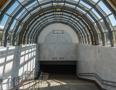 Metro içine iniş. Geniş bir merdiven ve bir kemer şeklinde bir cam çatı