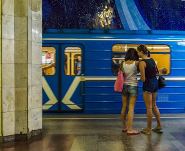 Lezbiyen çift ayakta tren sürme arka plan üzerinde Metro İstasyonu