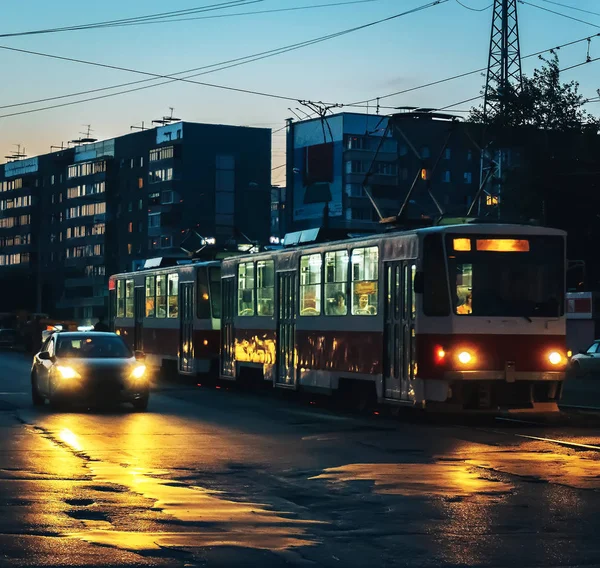 Tramwaj, samochód, Zmierzch, miasto, ludzie, reflektory, ciemny dom w tle — Zdjęcie stockowe