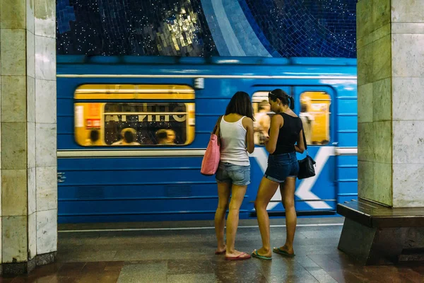 Dwie młode dziewczyny stojąc na stacji metra na tle jazdy pociągu — Zdjęcie stockowe