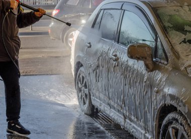 Temassız oto yıkama, köpük, basınç, self-servis. Adam arabasını yıkıyor