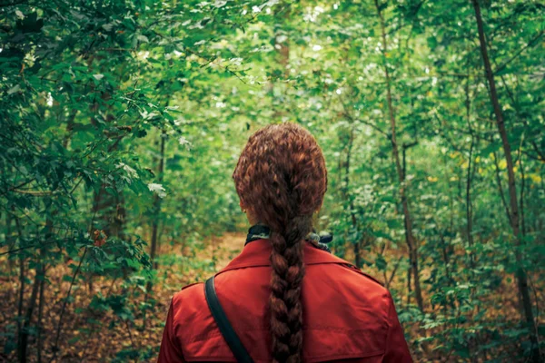 Baksidan på ung kvinna med långt hår lie promenader i skogen — Stockfoto