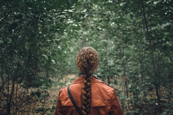 Ung kvinna med långt hår promenader i skogen. Bakifrån, dramatisk bild concepte — Stockfoto