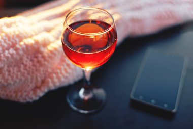 Kırmızı şarap ve beyaz battaniye ile hareket eden telefon. Güneşli akşam. Tonda bokeh görüntü.