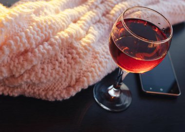 Kırmızı şarap ve beyaz battaniye ile hareket eden telefon. Güneşli akşam. Tonda bokeh görüntü.