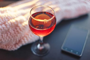 Kırmızı şarap ve beyaz battaniye ile hareket eden telefon. Güneşli akşam. Tonda bokeh görüntü.