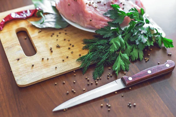 Carne cruda en tabla de cortar con verduras verdes, pimiento rojo, hoja de laurel y cuchillo — Foto de Stock