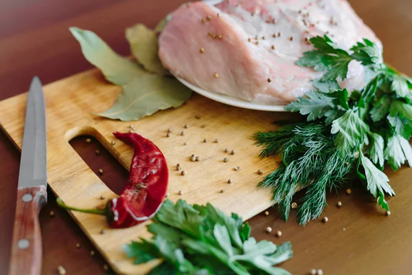 Carne cruda en tabla de cortar con verduras verdes, pimiento rojo, hoja de laurel, especias, cuchillo — Foto de Stock