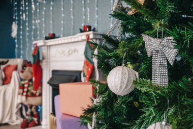 Baubles ve şömine başında bir arka plan üzerinde yay süslenmiş Noel ağacı 