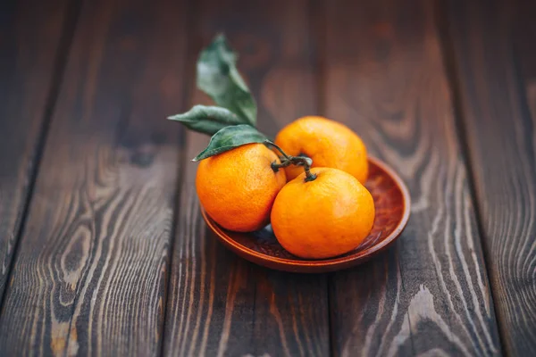 Mandariner på träplatta med blad på trä bakgrund närbild. ekologiska grönsaker — Stockfoto