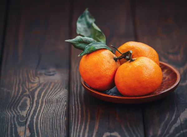 Suculentas tangerinas maduras com folhas no fundo de madeira close-up — Fotografia de Stock