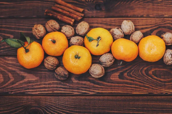 Свежие сочные спелые мандарины с листьями грецких орехов и корицы на дереве — стоковое фото