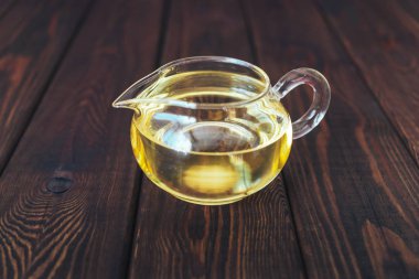 ahşap arka plan üzerinde yağ veya sarı çay ile küçük cam kavanoz