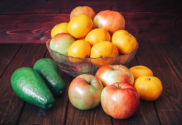 Свежие фрукты на столе: яблоки, мандарины и авокадо. Темный деревянный фон . — стоковое фото