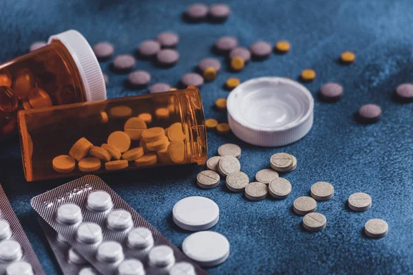 Лекарственные таблетки, таблетки и капсулы, пролитые из бутылки на стол — стоковое фото