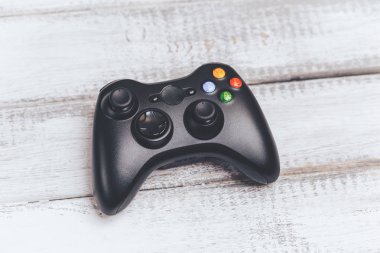 Beyaz ahşap masa üzerinde oyun konsolu için siyah kablosuz gamepad veya oyun denetleyicisi