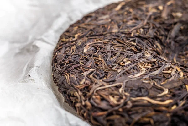 Staré Shen puerh čínských fermentovaný čaj na papyru papírové pozadí makro detail — Stock fotografie