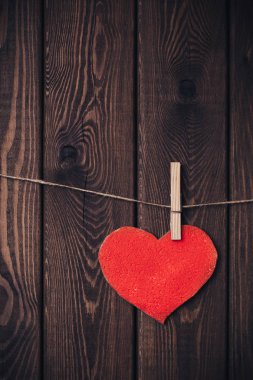 Clothespin ahşap zemin ile kırmızı kalp bir ip üzerinde. Uzay kopyalayın. Dikey