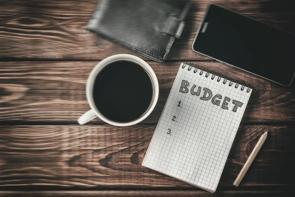 Költségvetési tervezés fogalma. A Jegyzettömb, a word költségvetés, mobil telefon, kupa felülnézet — Stock Fotó