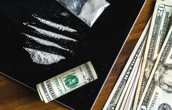 Líneas de cocaína y algunas pastillas de drogas en un paquete de plástico, billetes en dólares —  Fotos de Stock