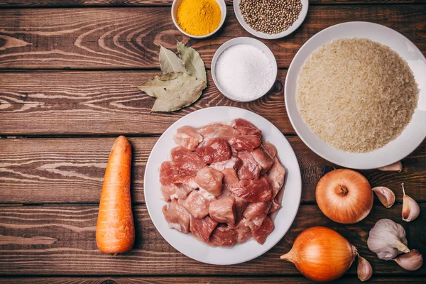 Vista superior de los ingredientes de cocina en tablero de madera rústica. Carne cruda, cebolla, zanahoria — Foto de Stock