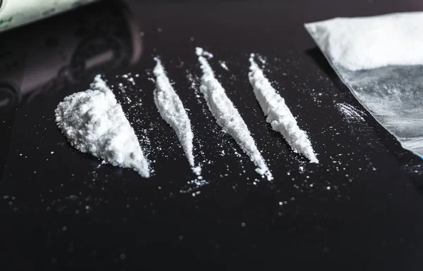 Toxicodependência de cocaína. Linhas de cocaína no fundo preto close-up — Fotografia de Stock