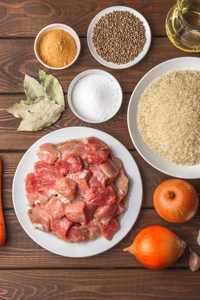 Componentes de cocina.Carne cruda en rodajas, arroz, especias, ajo, zanahoria, cebolla — Foto de Stock