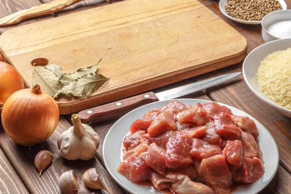 Cocinar ingredientes. Tabla de cortar. Carne cruda en rodajas, arroz, aceite, especias, ajo — Foto de Stock