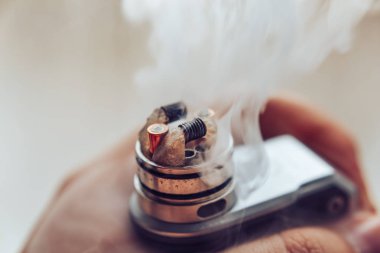 Vaping, vape aygıt için mod tutarak ve BKİ üst kapağı damlayan erkek eli
