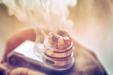 Vaping, vape aygıt için mod tutarak ve BKİ üst kapağı damlayan erkek eli