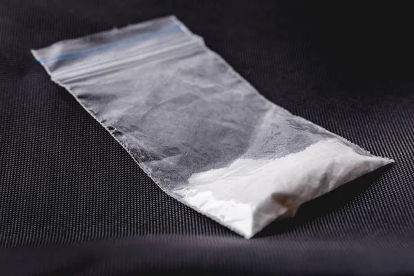 Κοκαΐνη σε πλαστικό πακέτο σε μαύρο φόντο, μακρο φωτογραφία κινηματογράφηση σε πρώτο πλάνο. Μερίδα — Φωτογραφία Αρχείου