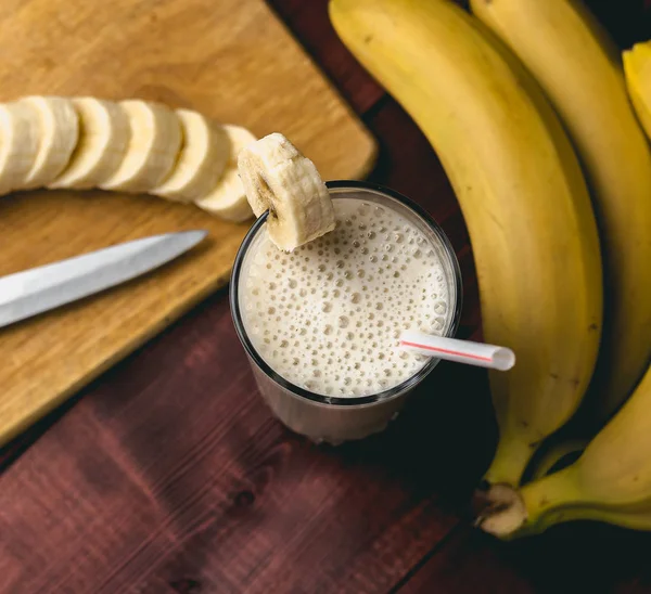 Batido de plátano casero fresco, tabla de cortar y plátanos en madera rústica oscura —  Fotos de Stock