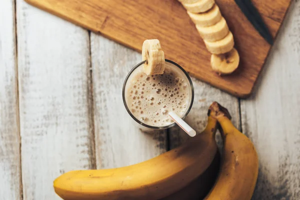 Smoothie banana caseiro fresco e bananas na mesa de madeira rústica branca, saudável — Fotografia de Stock