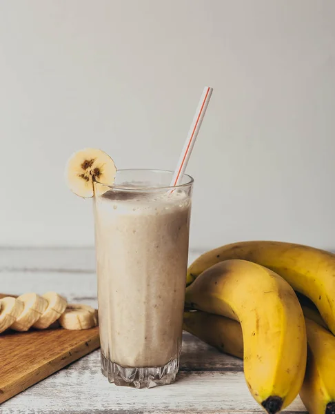 Smoothie à la banane fraîche maison, planche à découper et bananes sur bois rustique blanc — Photo