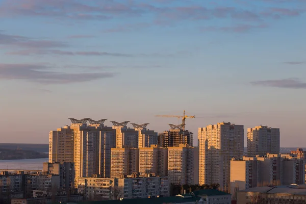 A construção de edifícios modernos de arranha-céus ao pôr-do-sol com guindaste — Fotografia de Stock