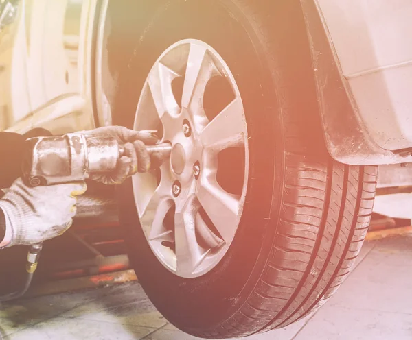 Close up van mechanische handen met pneumatische moersleutel wijzigingen wiel op auto — Stockfoto