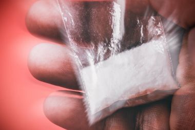 Uyuşturucu. Adamın elini tutar Plastik paket kokain ile yakın çekim 