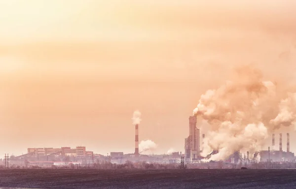 Fabrieken met rook uit pijpen vuile vervuilde industriële gebied in geel en oranje tinten — Stockfoto