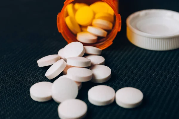 White tablets or pills are scattered from an orange pill bottle — Stock Photo, Image