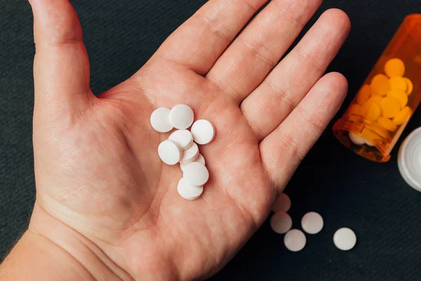 Handful of white pills in man's hand — Stock Photo, Image