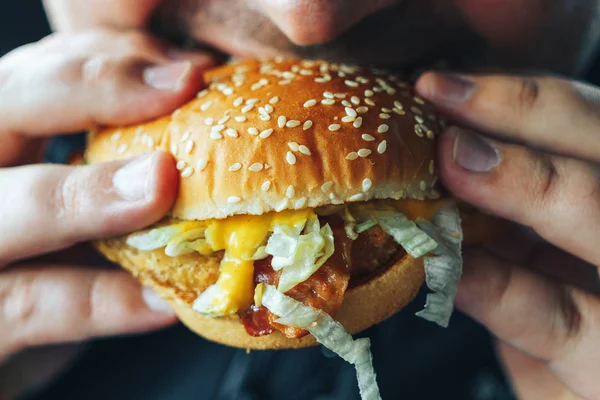 Mann hält und beißt Hamburger — Stockfoto
