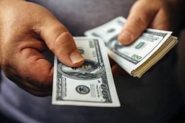 Yüz ABD Doları banknot veren ve nakit elinde tutan adam
