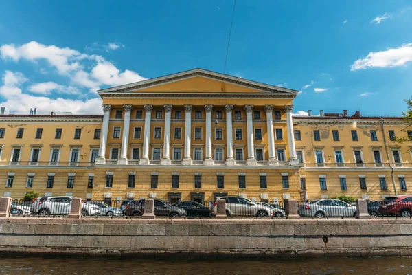 Nézd a víz, a szép sárga épület oszlopok töltésén St. Petersburg, Oroszország — Stock Fotó