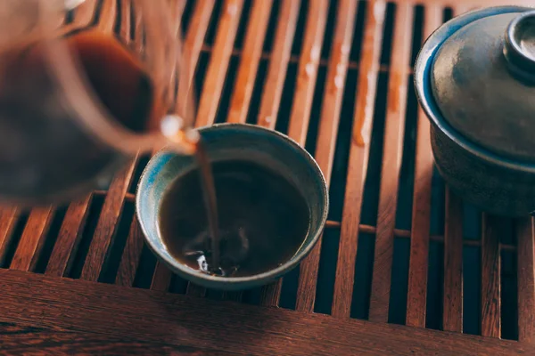 Xícara de chá chinês é derramado por chá preto fresco quente — Fotografia de Stock