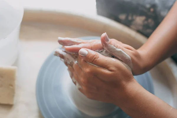 As mãos de oleiro feminino jovem trabalham com barro branco na roda de cerâmica — Fotografia de Stock