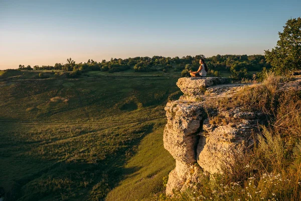 Genç hipster kenar cliff üzerinde oturur ve derin derin düşünür
